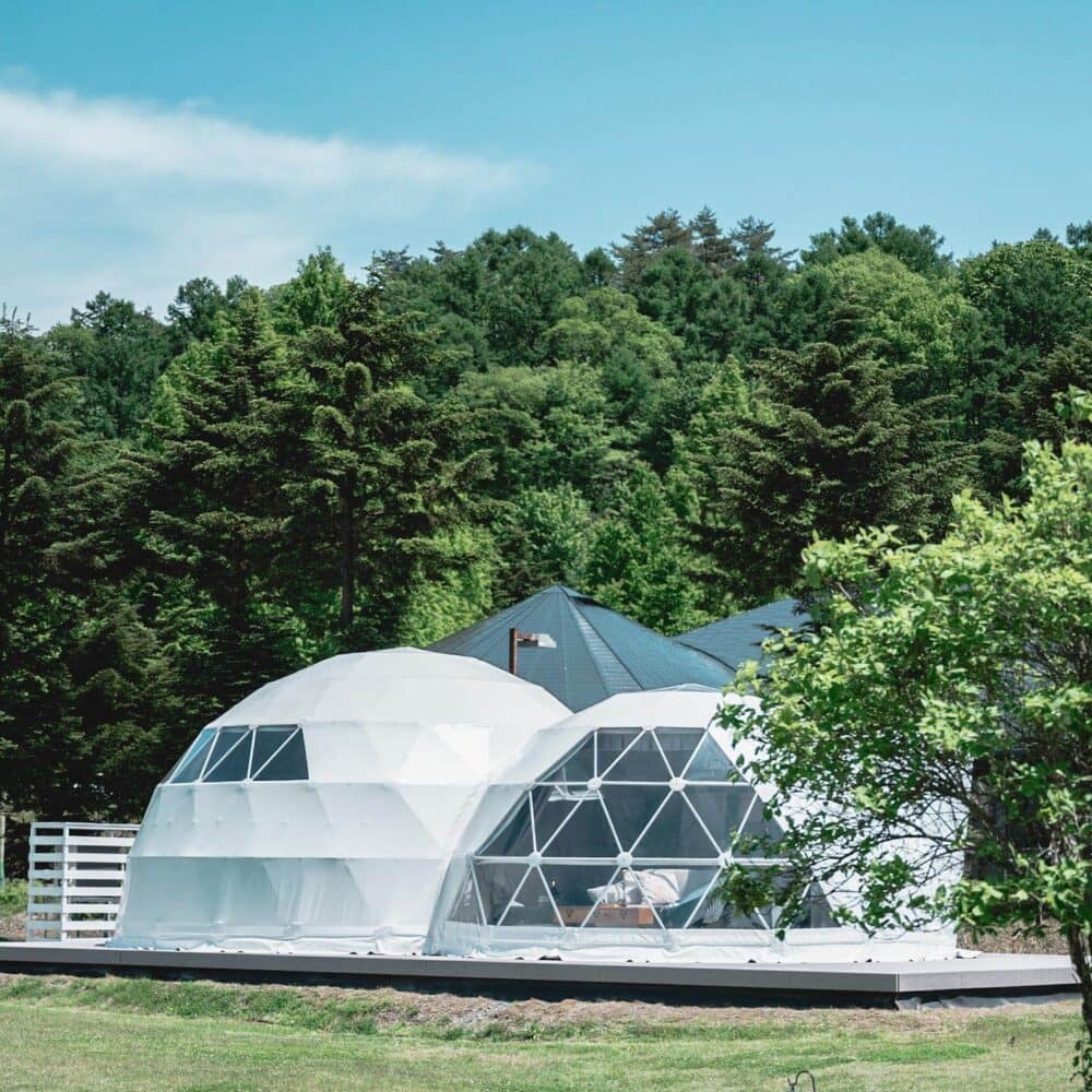 Two white domes in the middle of a field offering a unique Glamping experience at Glamprook Iizuna in Japan.