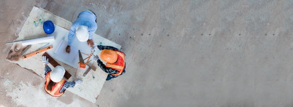 A group of construction workers are sitting on a concrete floor at the North Dakota State Fairgrounds.