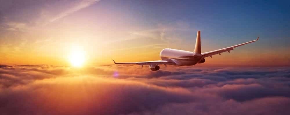 A record-setting airplane flying through the clouds at sunset.