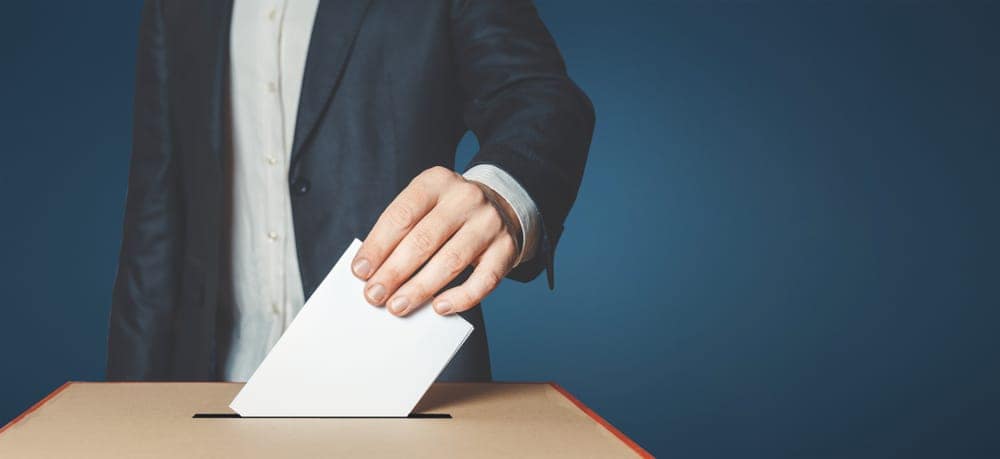 A man is putting a paper into a voting box as Alabamans cast their vote.
