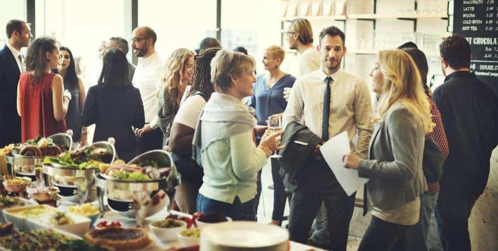 A group of people standing around a buffet table at a conference.