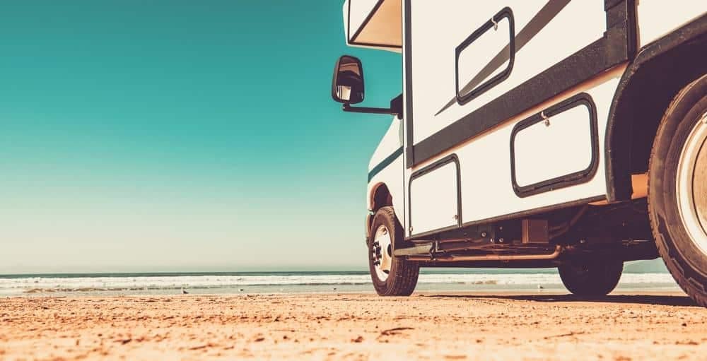 Go RVing's rv is parked on the beach next to the ocean.