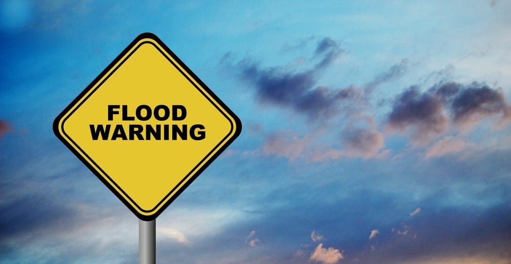 Evacuations advised as flood warning sign stands against a cloudy sky in Whitecourt.