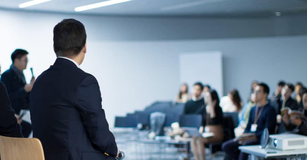 A man in a suit is giving a presentation to a group of Caravan Owners.