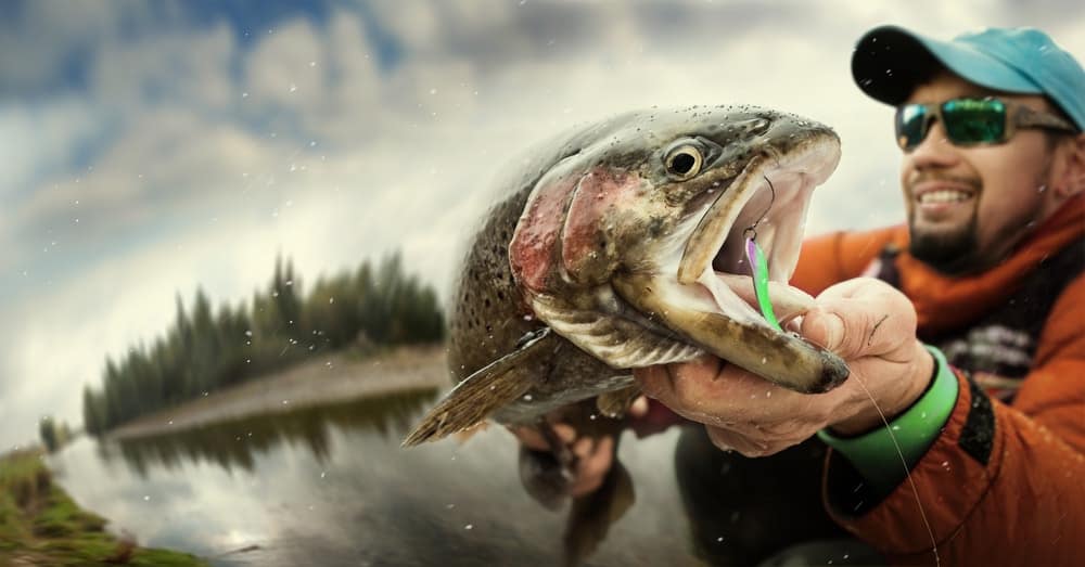 A man is holding a fish in his hand on U.S. Fish and Wildlife Managed Lands.