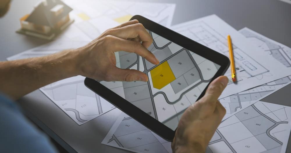 ミットン ゲッタウェイズ グランピング リゾート開発地で、地図が載ったタブレットを持ち、道案内をしている人物。