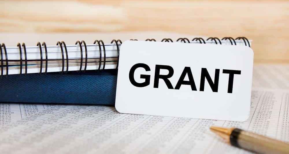 A note with the word grant sitting on top of a notebook.