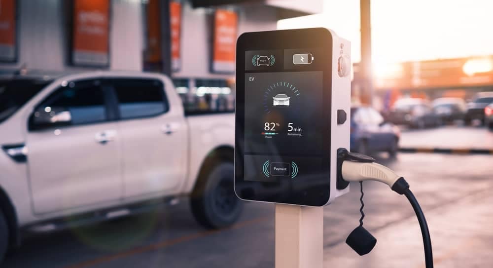 An electrifying white truck is parked next to an electric charging station, attracting RVers at campgrounds.
