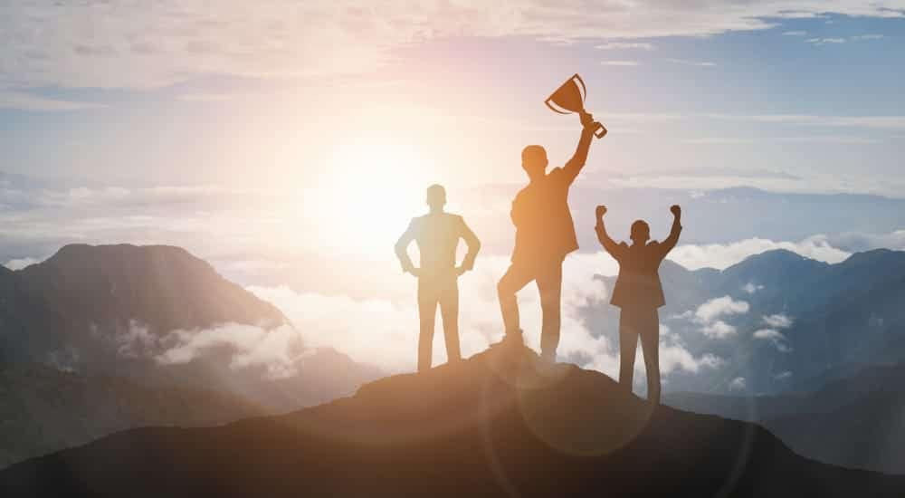 Business people standing on top of a mountain, showcasing their lifetime achievement.