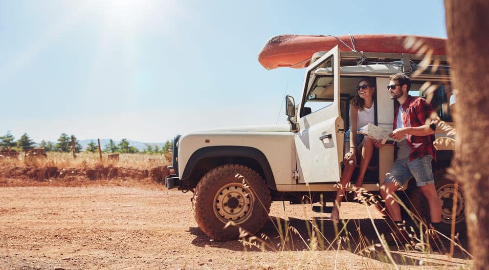A group of Roadtrippers sitting in the back of a jeep on a dirt road, enjoying the Restaurants and Nightlife along their journey with Yelp Integration.