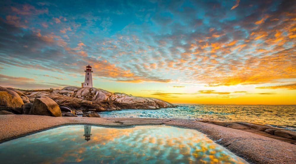 Your Ocean Playground in Nova Scotia welcomes tourists to a breathtaking lighthouse with a pool in the middle of the ocean at sunset.