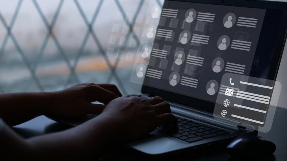 A person typing on a laptop with social network icons on the screen, circulating their full directory.