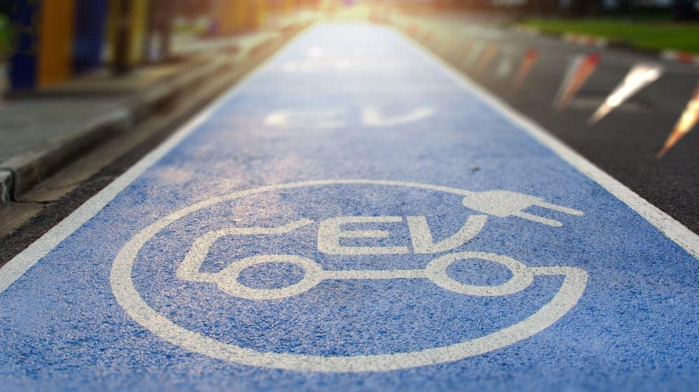 An EV-Ready sign on a road with a car on it.