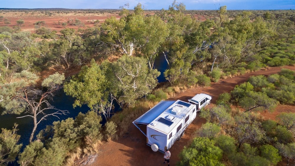 An aerial view of an RV parked next to a river in the outback, showcasing the expanding RV sharing industry facilitated by Camplify Holdings.
