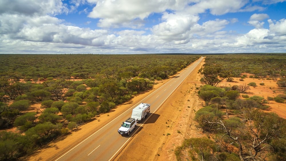 An aerial view of a truck driving down a desert road in Australia.