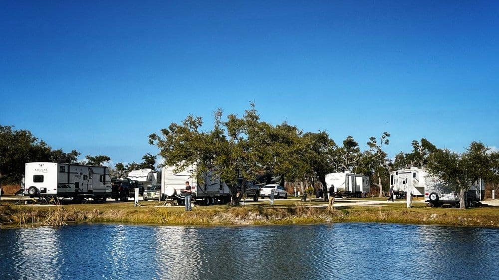 Located at Quilly's Big Fish RV Park, this scenic spot offers stunning views of a lake where a group of rvs can be found parked.