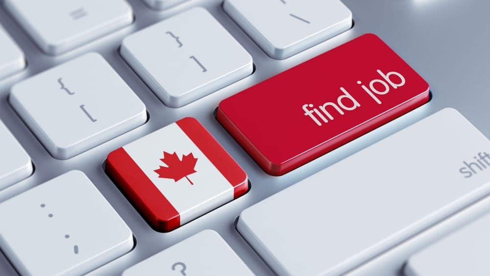 A Canadian flag on a keyboard with the word find job, illustrating the current labor shortage in Canada.