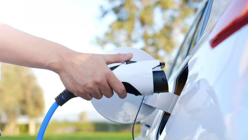 A person in Alabama is charging a white car with a blue cord.