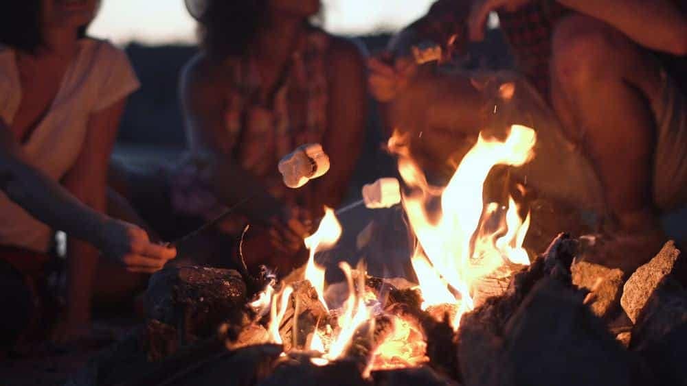A group of friends at the Pike County Campground sitting around a campfire at dusk, enjoying their evening with liability protections under Ohio legislation.