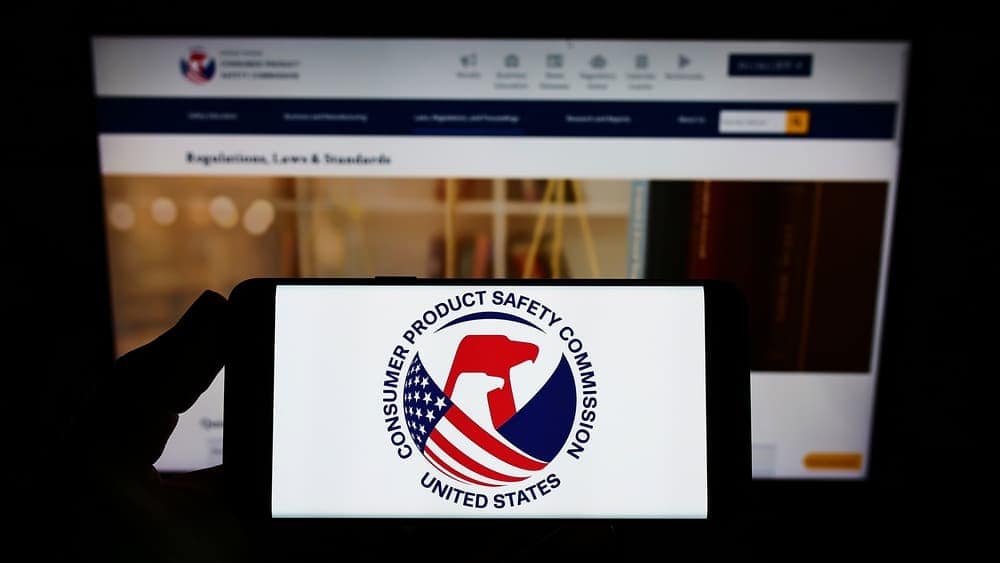 A person is holding up a cell phone with the uspc logo on it, without any mentions of recalls, Prestone, or antifreeze.