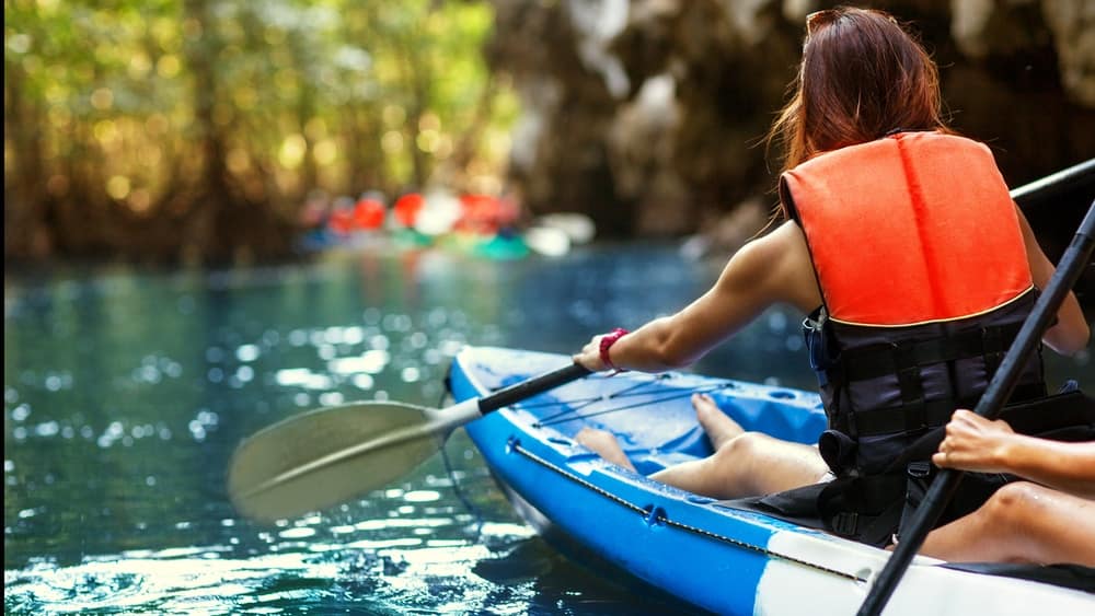 Two women paddling a kayak through a cave during a camping trip at RiverWalk RV Park in North Carolina.