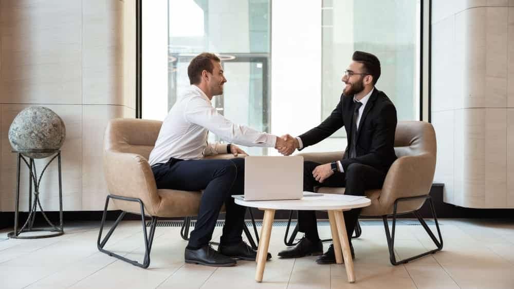 Two businessmen shaking hands in an office during a business meeting with the Chief Business Development Officer of Lippert in EMEA.