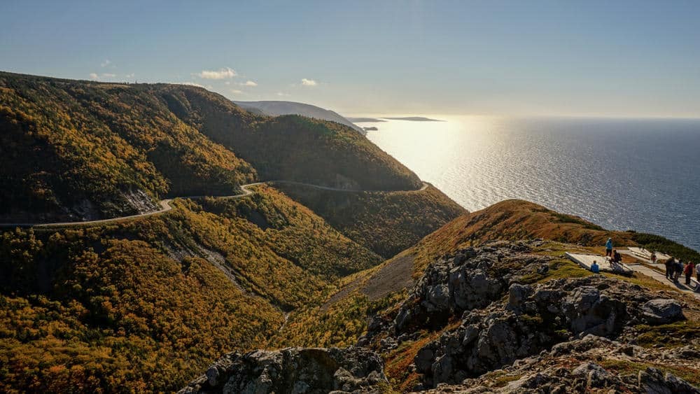 Visitors Bouncing Back in Cape Breton Highlands National Park, standing on a cliff overlooking the ocean.