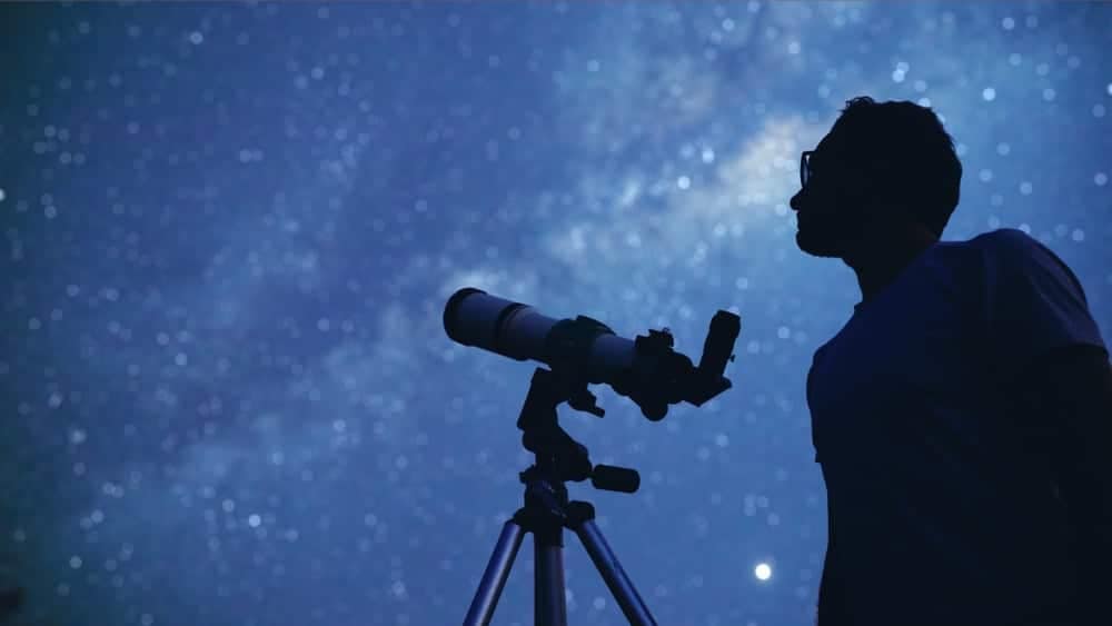 A man participating in the Stargazing Festival at Jasper National Park, observing the stars with a telescope.