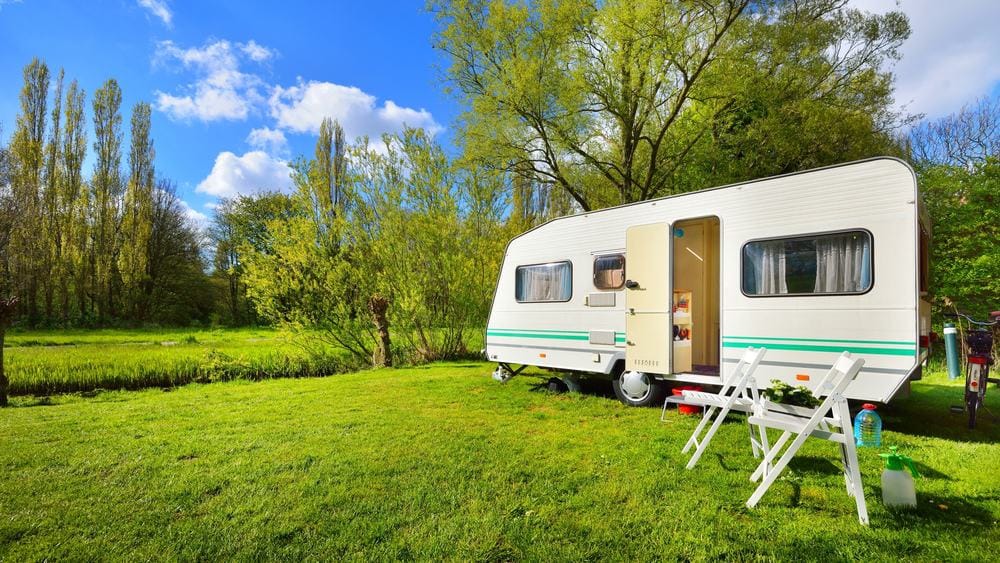 A LeadingCampings camper trailer parked on a grassy field in Europe during the Camping Boom.