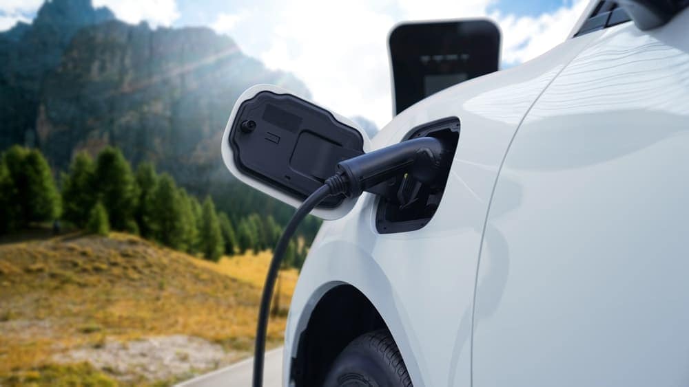 A white car in Canada is plugged into an electric charger.