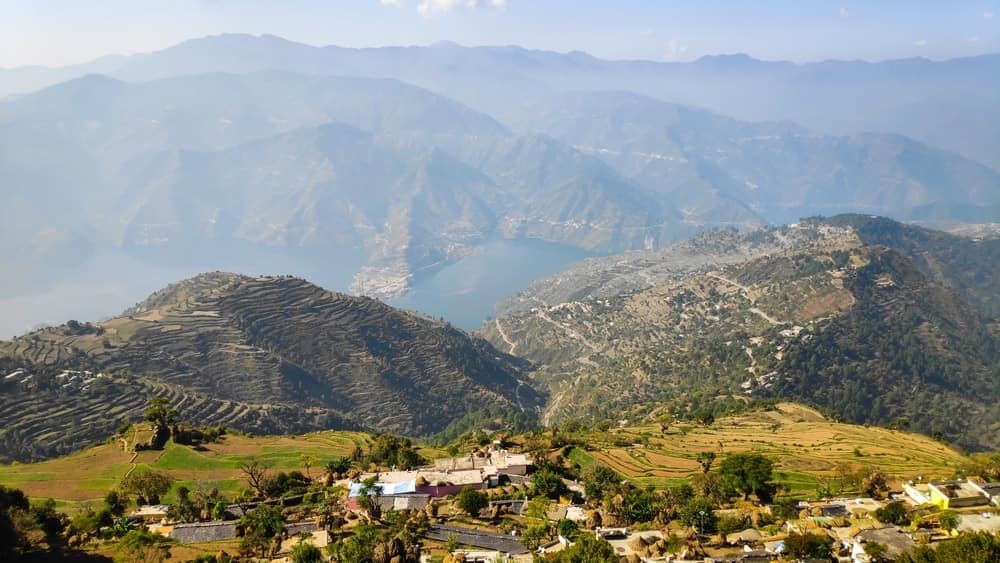 Dev Bhoomi Uttarakhand - A view of a village in the mountains with Nature's Splendor, a lake in the background.