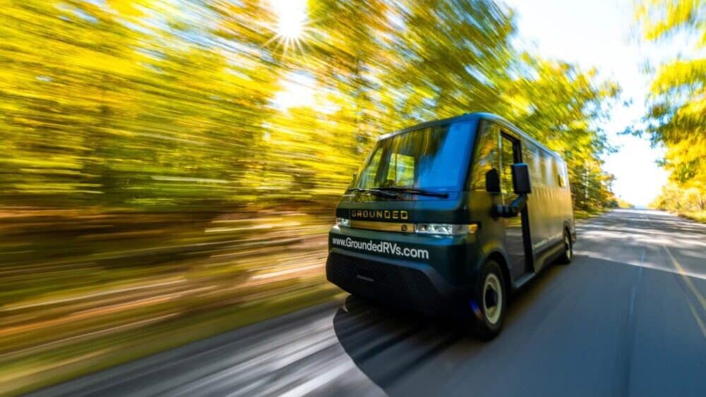 A G2 electric RV van driving down a road with trees in the background.