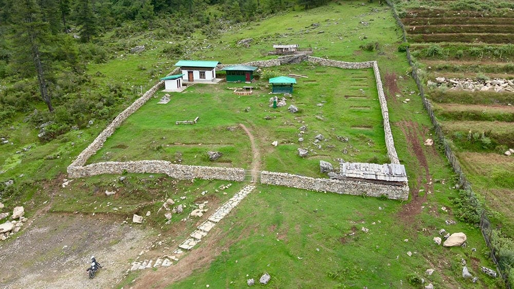 Rural mountain settlement with stone fences, small buildings, and terraced fields in the Gangtey-Phobjikha Valley.