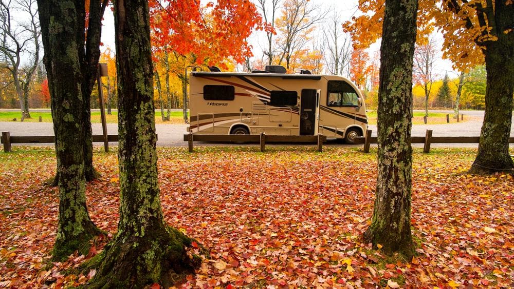 An rv parked in a park with autumn leaves, perfect for a peaceful getaway in Wisconsin Campgrounds.