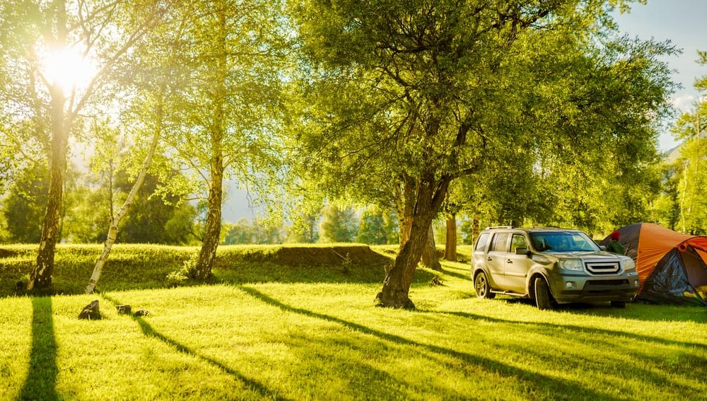 A suv parked next to a tent in a grassy field, WaterSense.