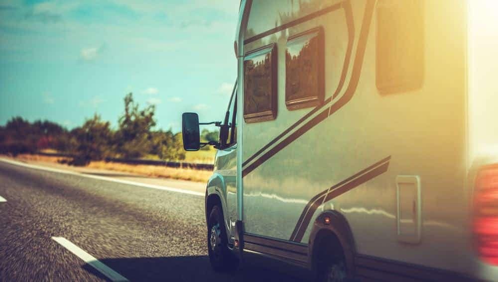 An rv is driving down the road on a sunny day.