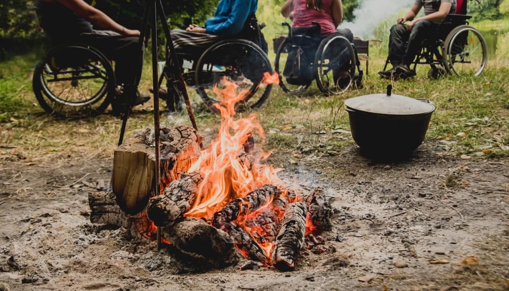 A group of people in wheelchairs around a campfire.
