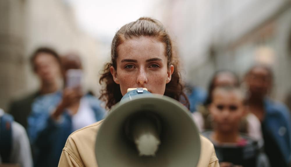 A woman holding a megaphone in front of a crowd of International Tourists at a National Park Reservation System event in Utah.