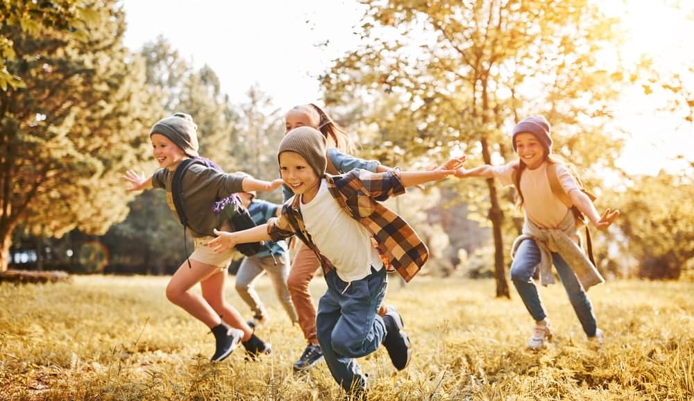 Development Director, Tyler Carter, oversees a group of children running joyfully in a field at Care Camps.