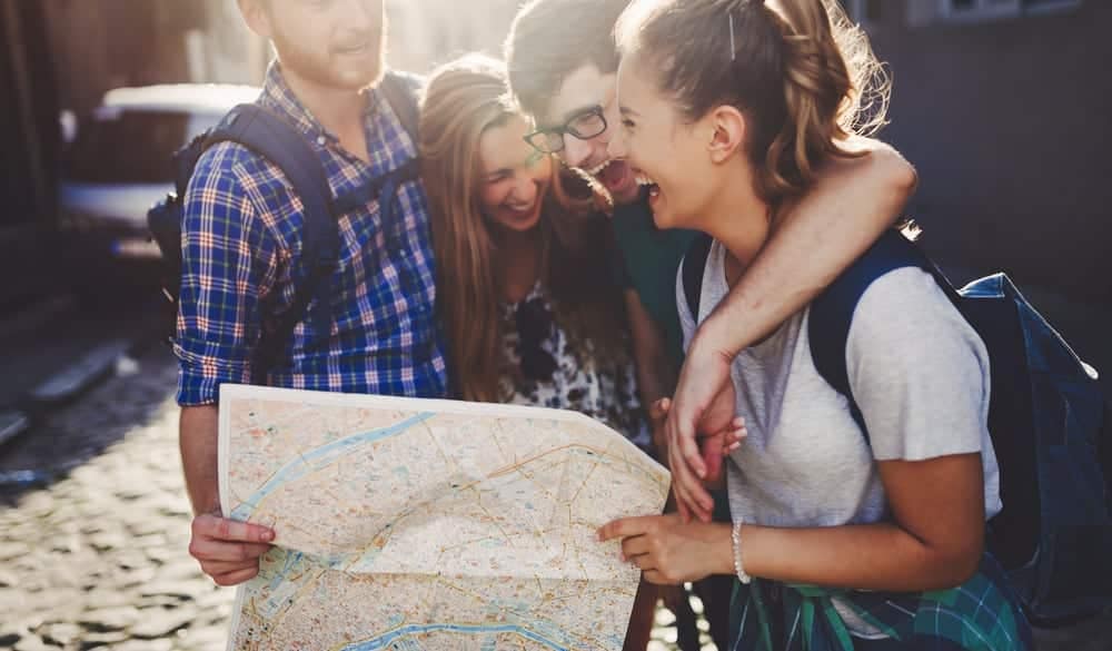 A group of friends planning their Memorial Day Weekend travel itinerary while consulting an AAA map.