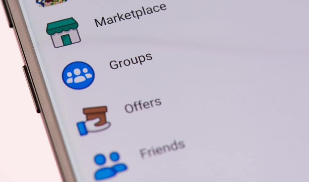 A smartphone is shown with a group of people on it, selling illegal campground reservations in Alberta Parks.