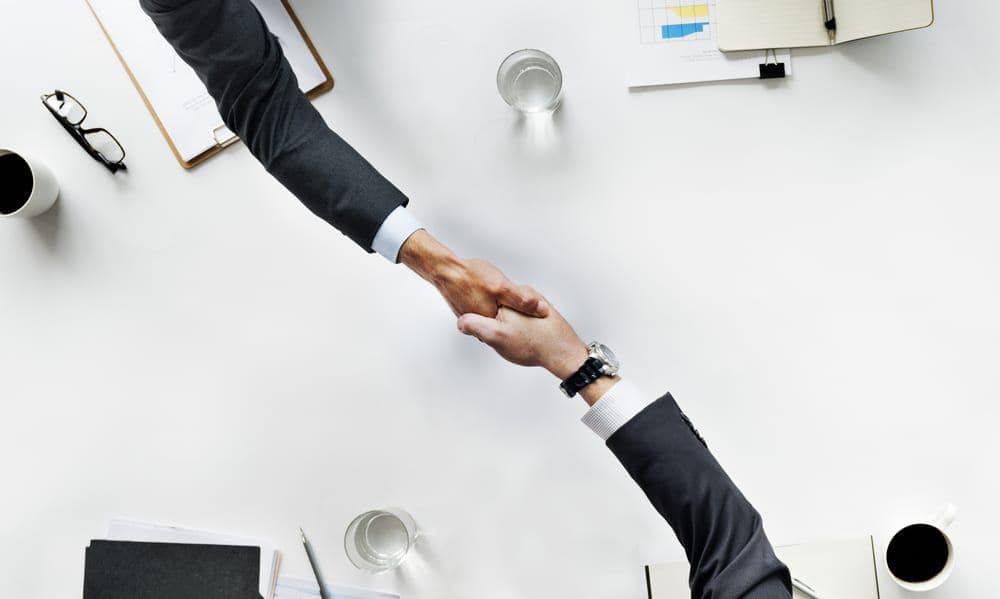 Two businessmen shaking hands at a table.