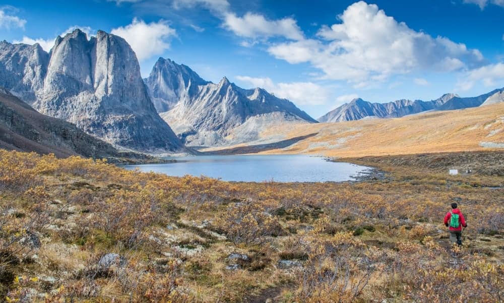 A man is hiking in the Yukon mountains near a lake.