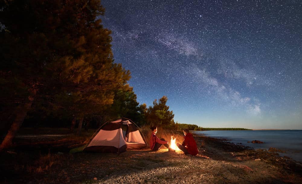 A couple enjoys a Romantic Valentine's Day Dinner around a campfire under a starry sky at one of the Tennessee State Parks.