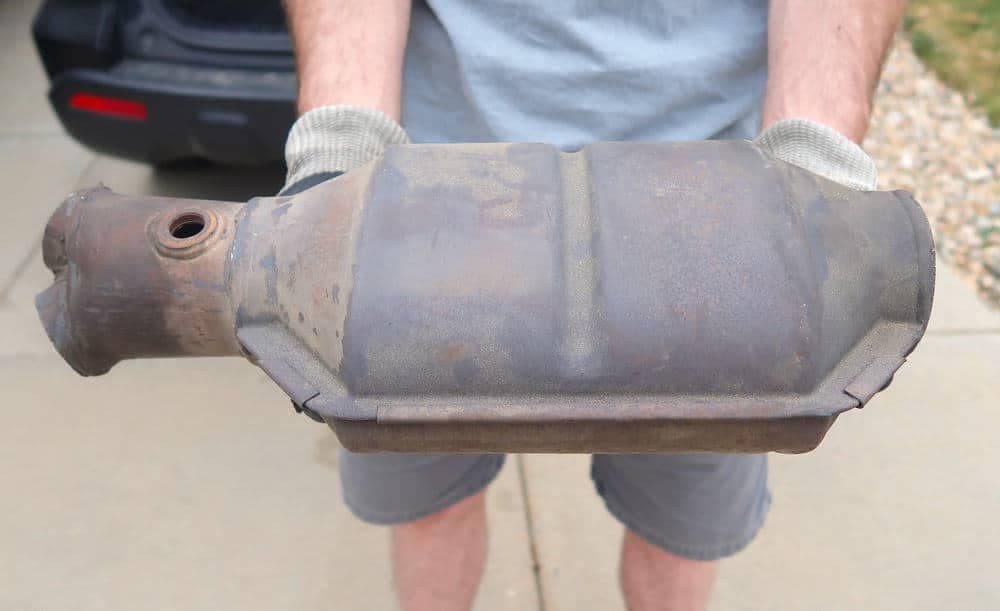 A man holding an old catalytic converter, amidst the rising incidents of RV catalytic converter thefts in New York, which have prompted vigilant law enforcement efforts.
