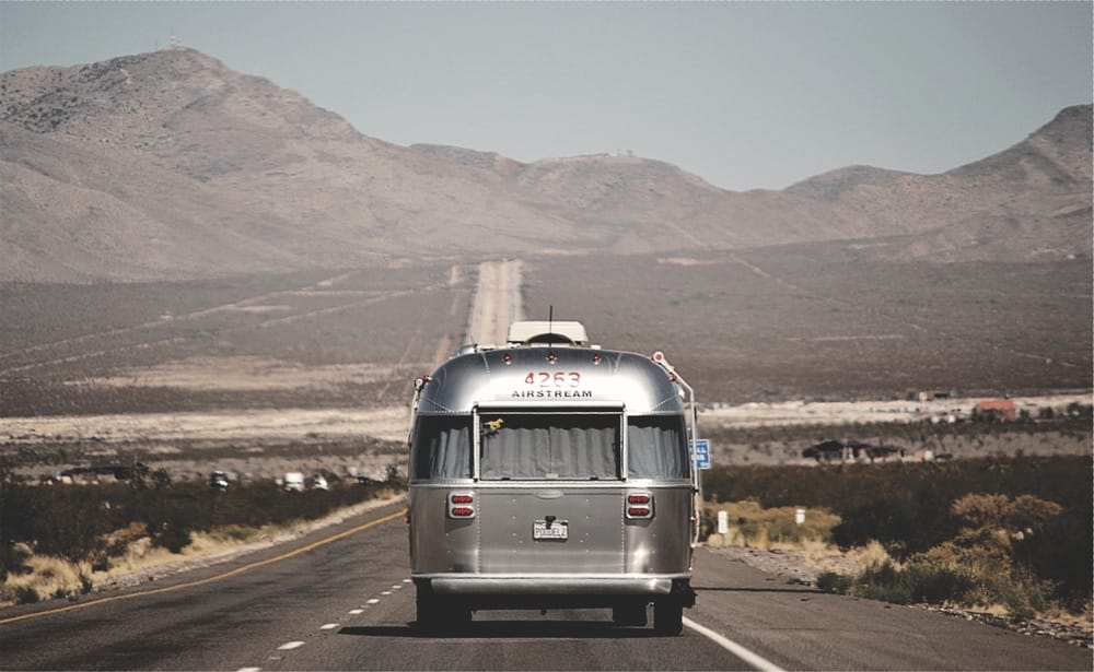 A 2021 silver Airstream traveling down a desert road.