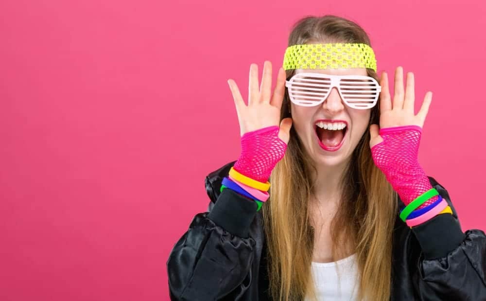 A young woman in a colorful outfit with sunglasses and a pink background at the National ARVC networking reception, giving off a 1980s-themed vibe.