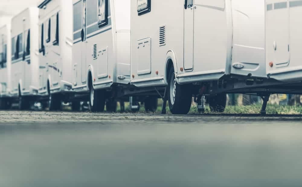 A row of white RVs parked in an industry parking lot.