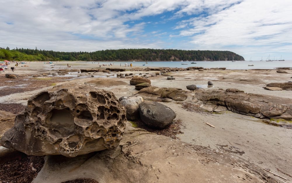 Camping on a beach with stunning rock formations near a body of water, providing the perfect outdoor recreational opportunity for land enthusiasts.