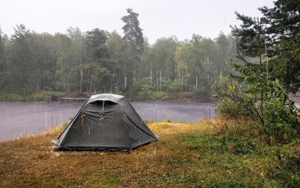 A tent is set up near a lake in the Manitoba Provincial Campgrounds, despite the wet weather.